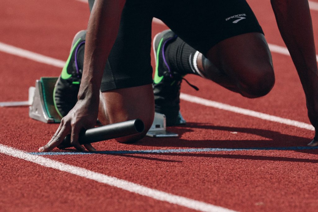 Athlete at starting line on track holding a baton ready for relay race