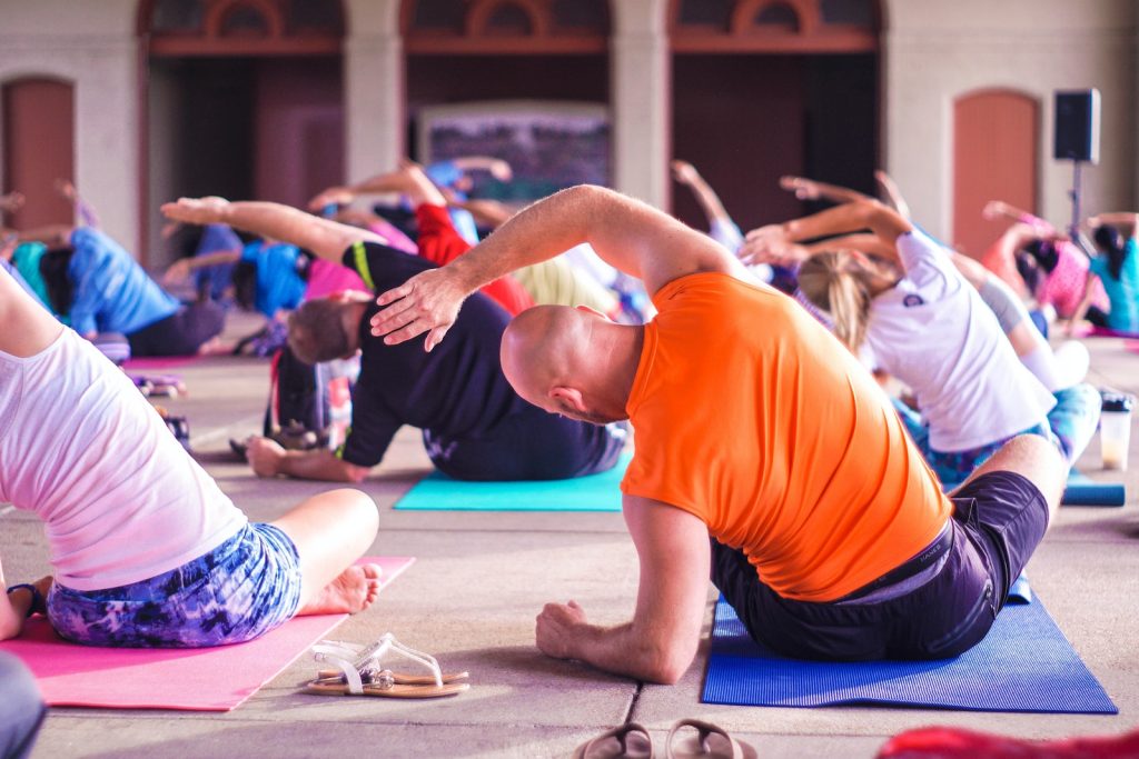 Group yoga class stretching on colourful mats indoors, focusing on wellness and flexibility